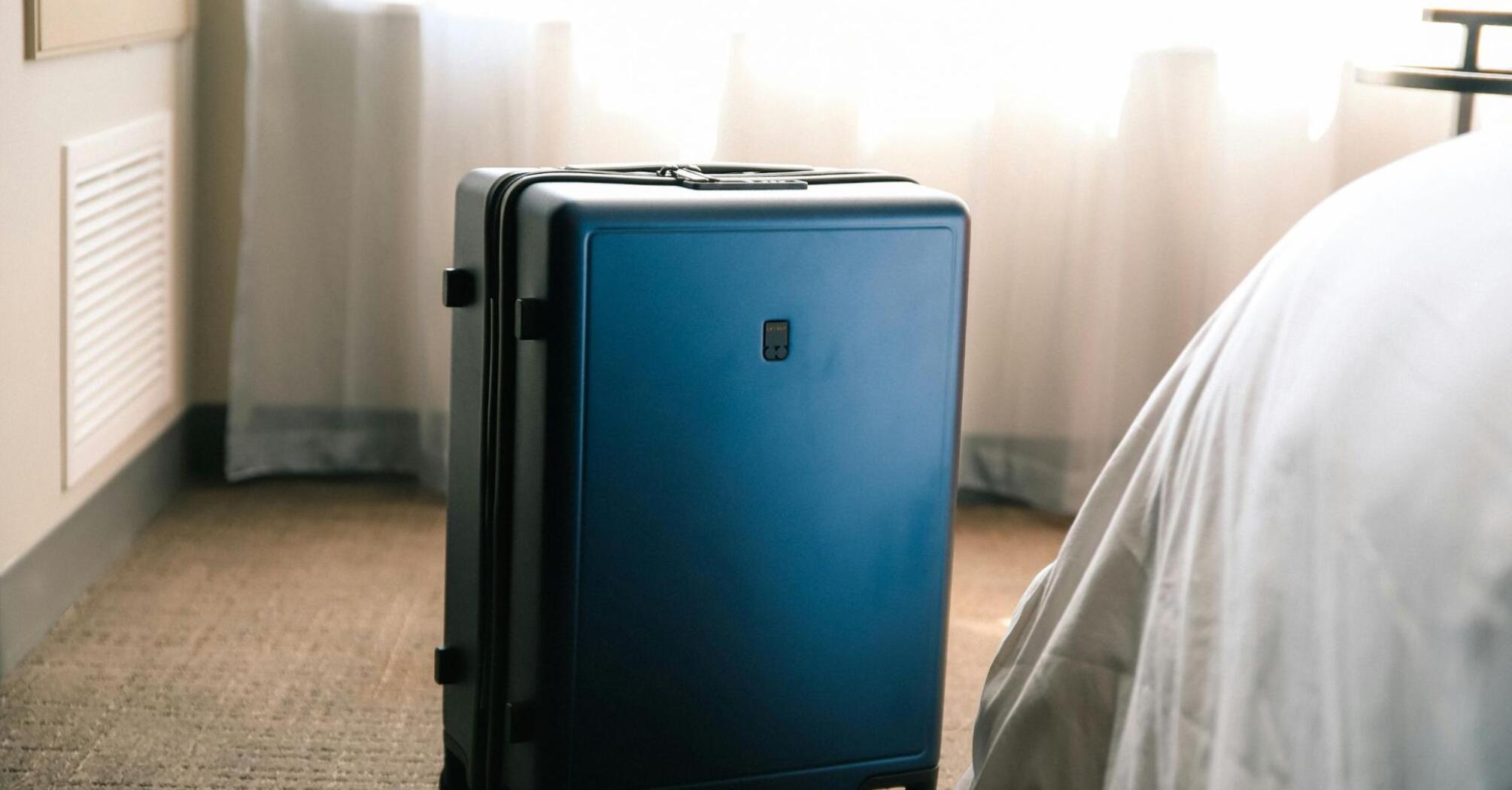 Suitcase standing near the bed in the room