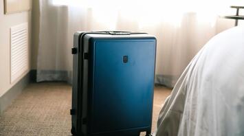 Suitcase standing near the bed in the room