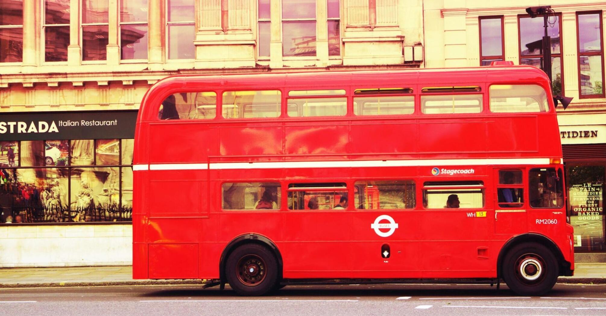 A classic red double-decker Stagecoach bus parked in front of a building with a restaurant sign