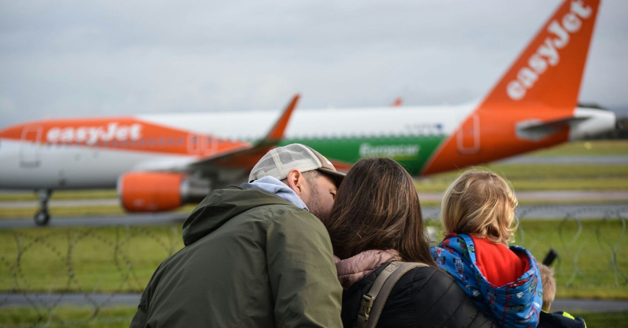 Family watching EasyJet plane on the runway