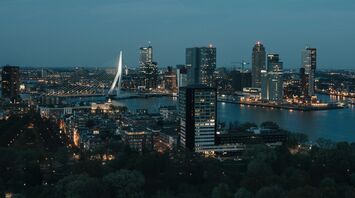 Rotterdam city skyline at night with illuminated buildings and Erasmus Bridge