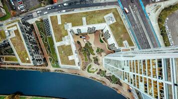 Aerial view of a modern cityscape in a Stratford-upon-Avon with green rooftops and a river running alongside high-rise buildings