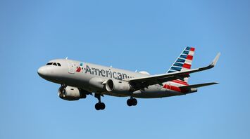 American Airlines airplane flying against a clear blue sky