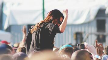 A girl enjoys music at a concert among a crowd of spectators
