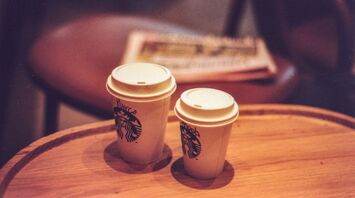 Two Starbucks coffee cups on a wooden table