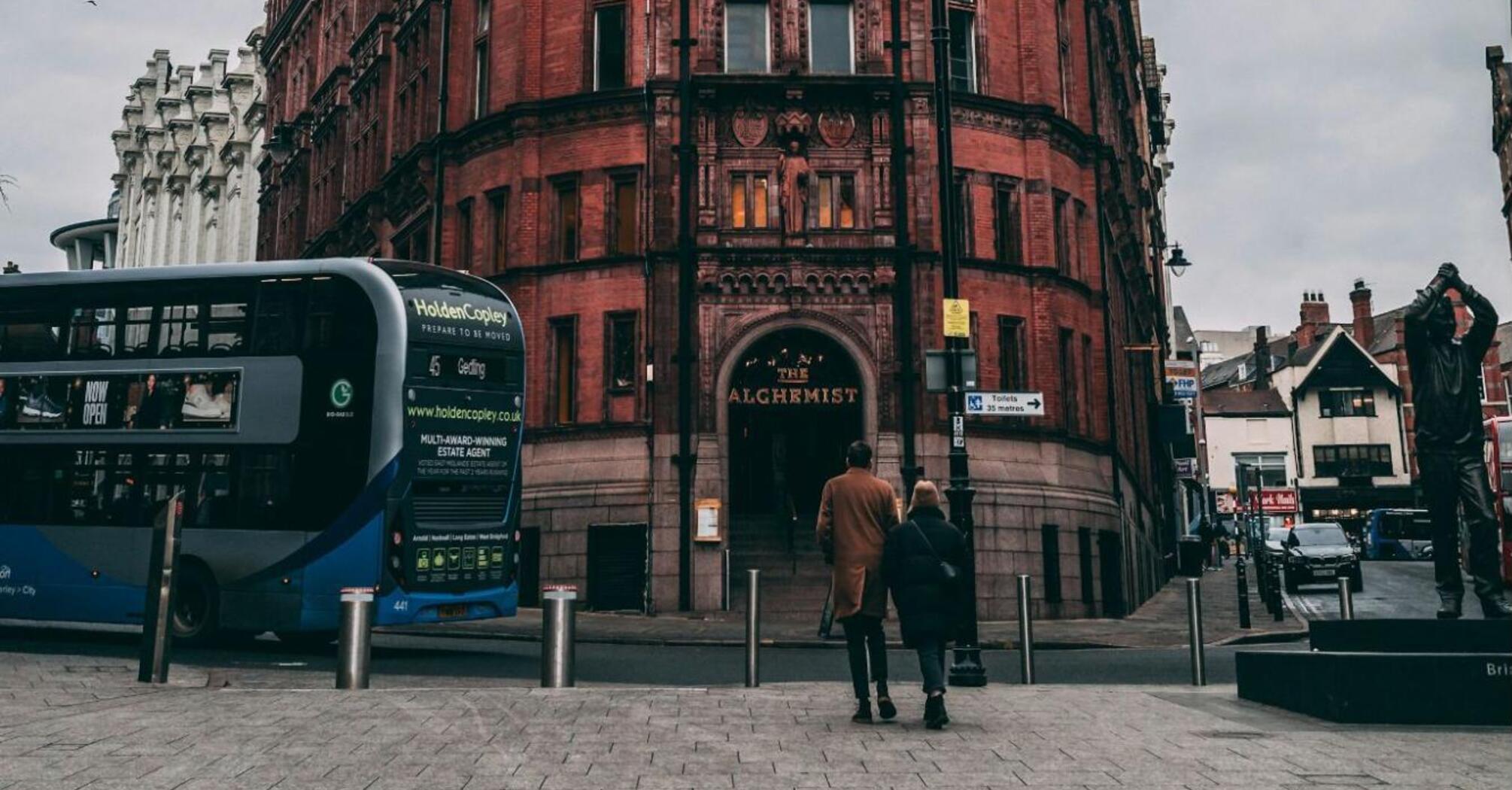 A red-brick building with a bus and pedestrians in Nottingham city center