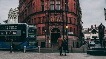 A red-brick building with a bus and pedestrians in Nottingham city center
