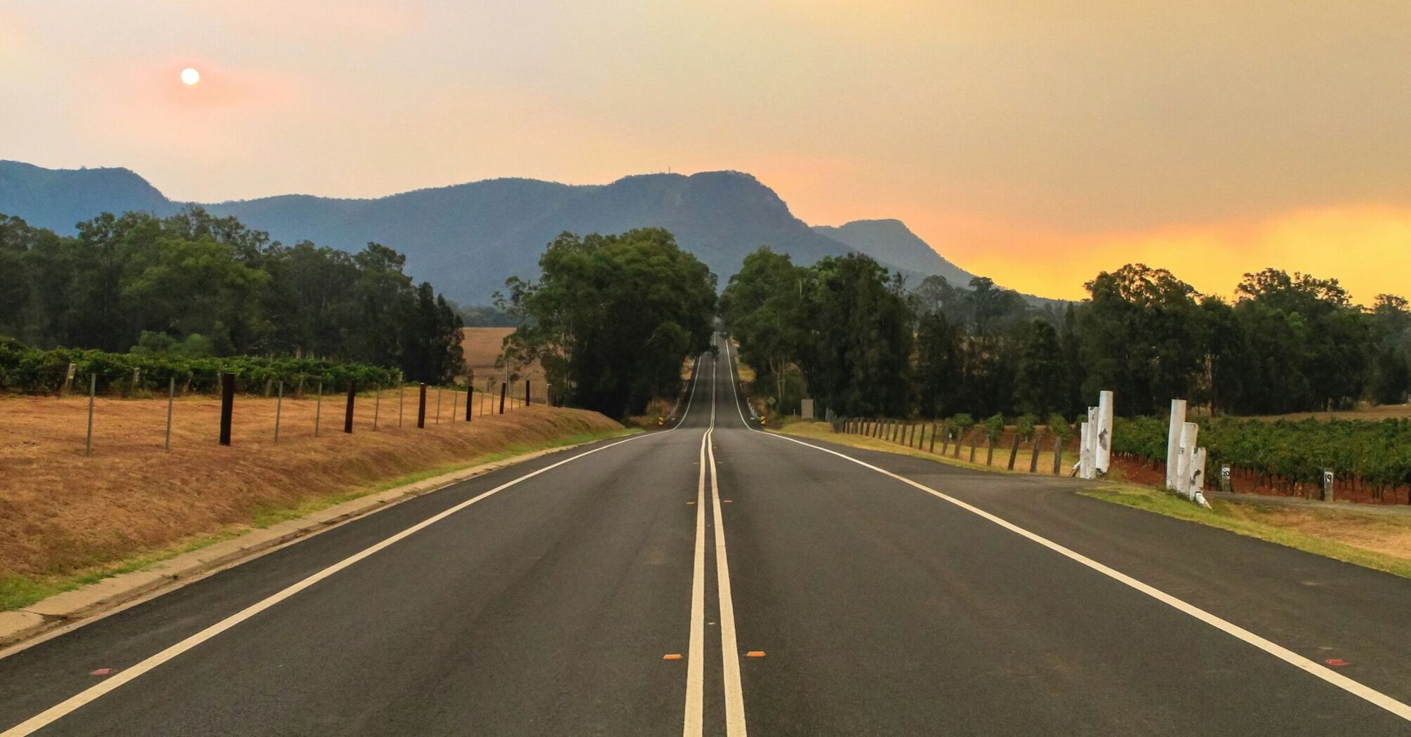 A long road leading towards mountains at sunset