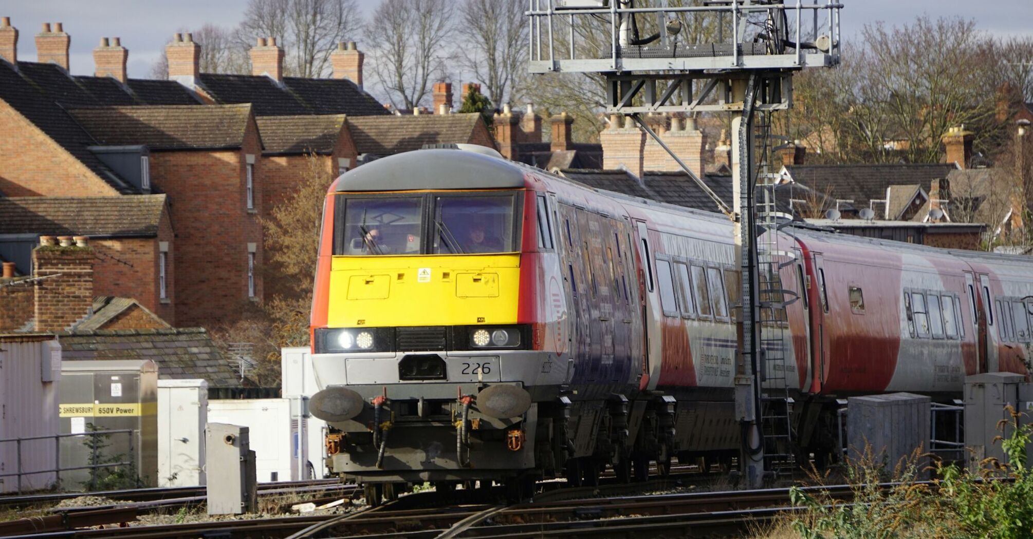 A Transport for Wales train approaches a railway station with residential houses in the background