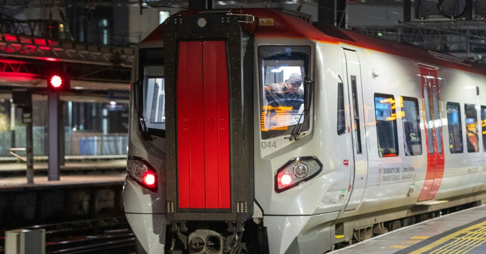 A Transport for Wales train at platform at a railway station in Manchester during the night