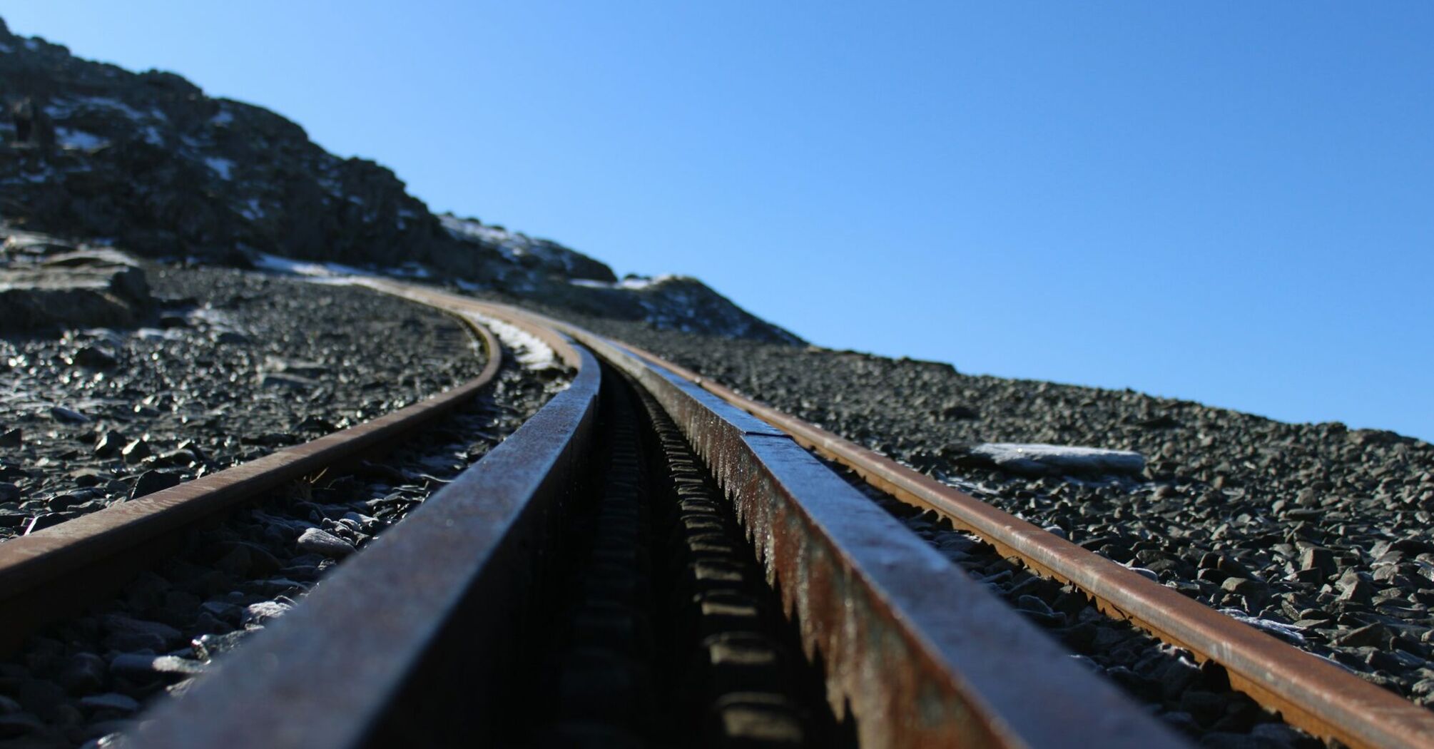 Close-up view of railway tracks on a rocky slope under a clear blue sky