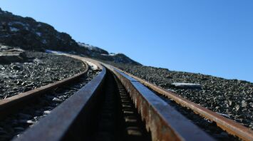 Close-up view of railway tracks on a rocky slope under a clear blue sky