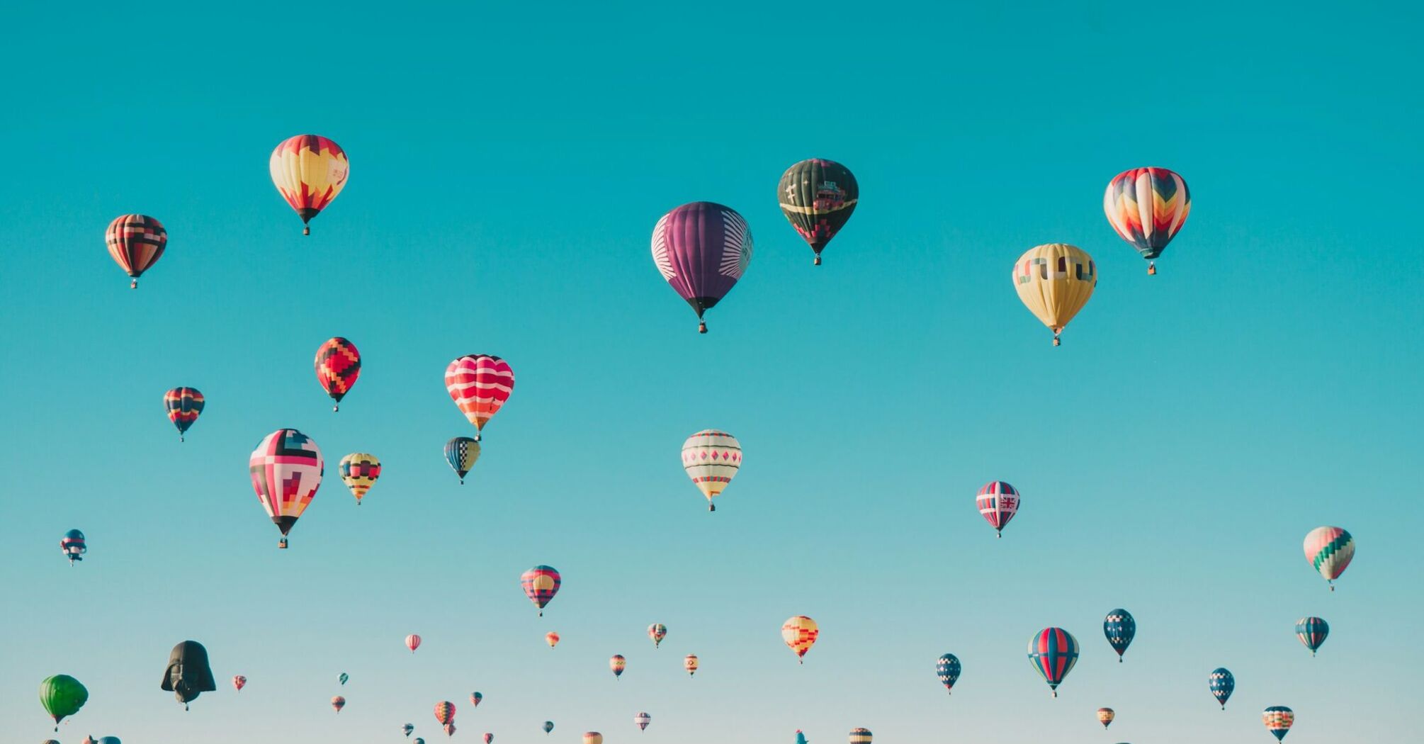 A clear blue sky filled with numerous colorful hot air balloons floating peacefully