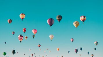 A clear blue sky filled with numerous colorful hot air balloons floating peacefully