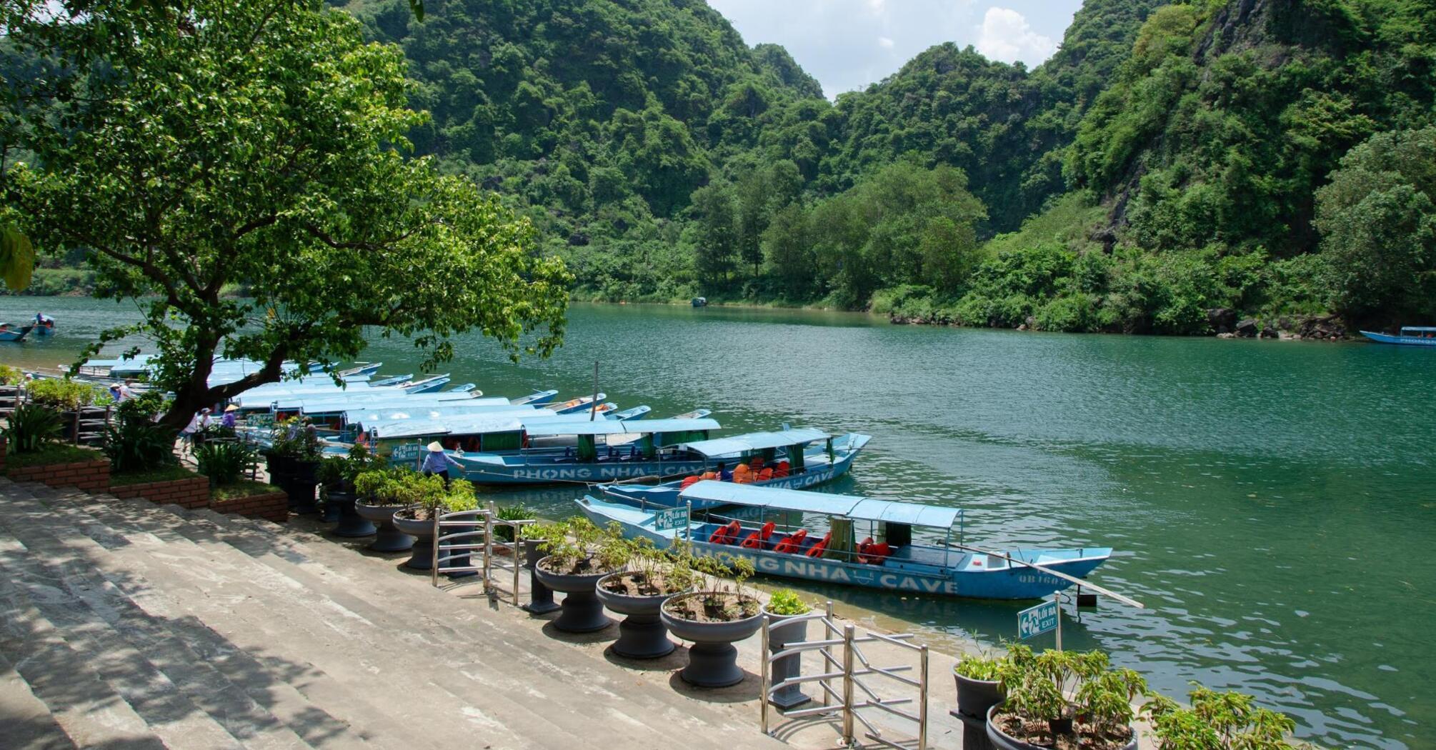 Boats on the river with green hills at Phong Nha Cave