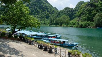 Boats on the river with green hills at Phong Nha Cave
