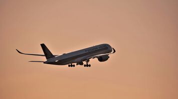 a large jetliner flying through a pink sky