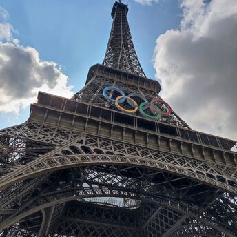 The Eiffel Tower with Olympic rings under a partly cloudy sky in Paris