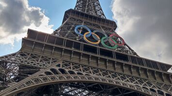 The Eiffel Tower with Olympic rings under a partly cloudy sky in Paris