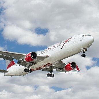 white and red flying airplane under white clouds