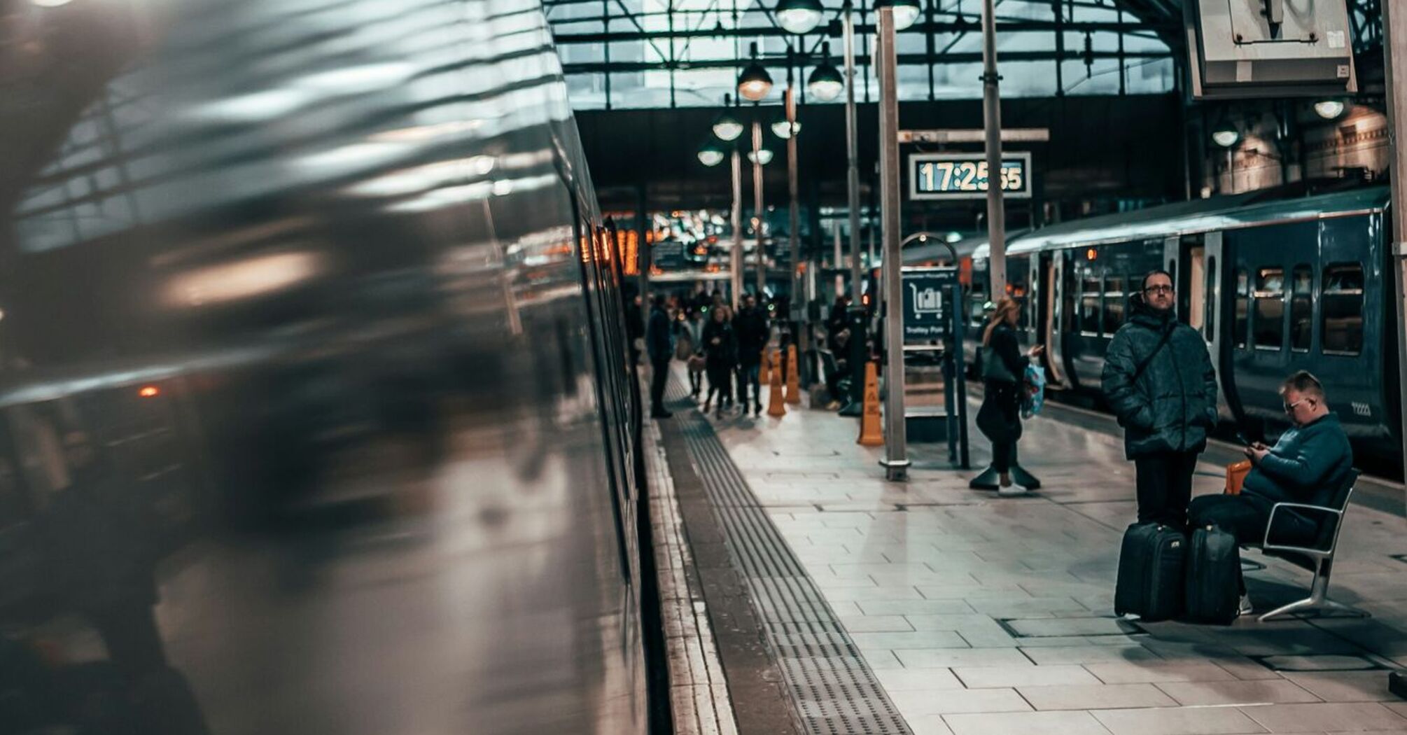 A view of a busy train platform inside a Manchester station with travelers waiting and trains on either side