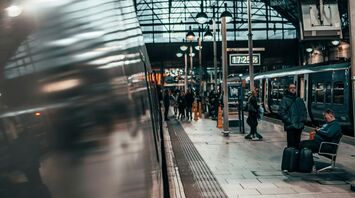 A view of a busy train platform inside a Manchester station with travelers waiting and trains on either side