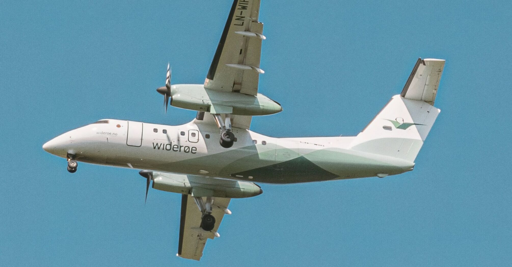 Widerøe aircraft flying against a clear blue sky