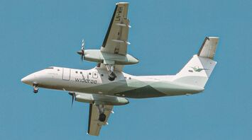 Widerøe aircraft flying against a clear blue sky