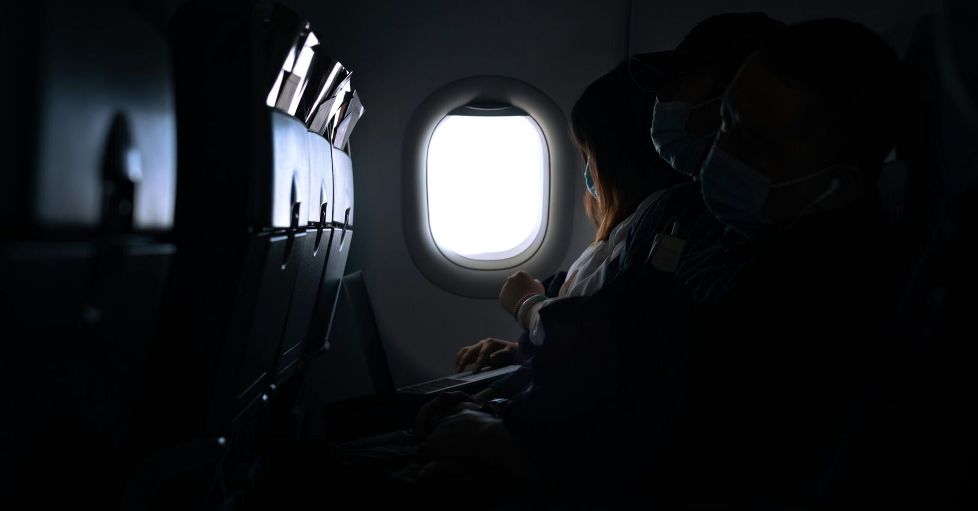 Passengers seated on a dimly lit airplane during a flight