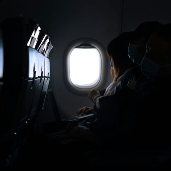 Passengers seated on a dimly lit airplane during a flight