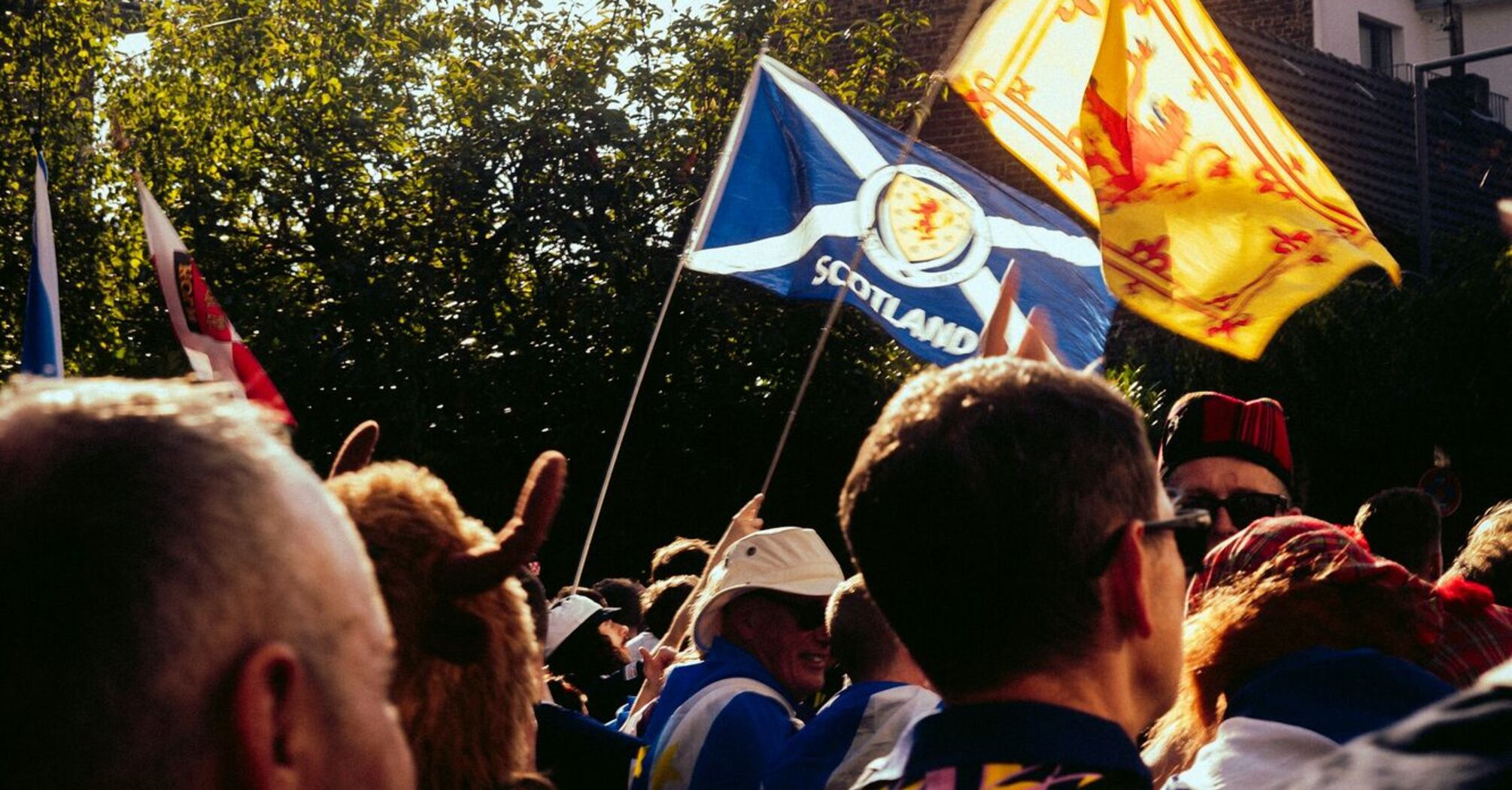 A crowd of football fans in Scotland, waving Scottish flags in a festive atmosphere