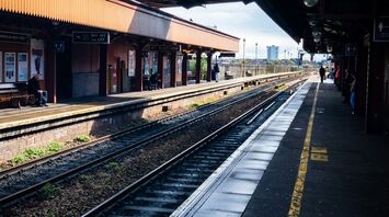A nearly empty railway station platform in Birmingham with tracks and an overpass bridge in view