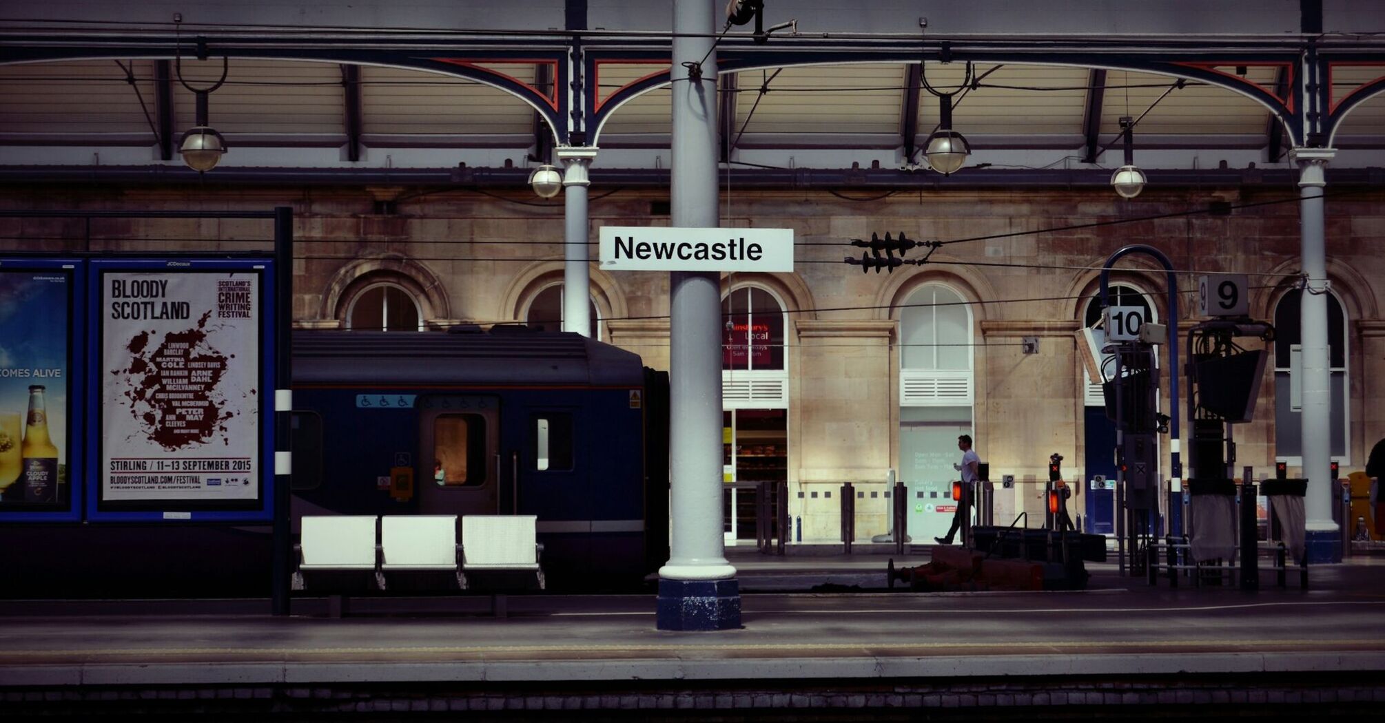 Newcastle train station platform with signs and a waiting train