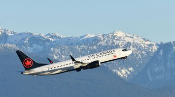 an air canada airplane flying over a mountain range