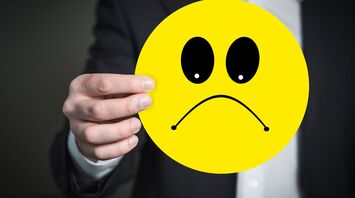 Person holding a yellow sad face emoji
