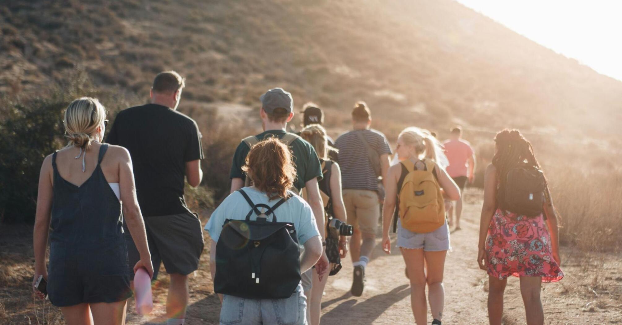 A group of people hiking on a mountain trail at sunset