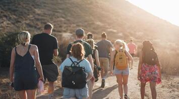 A group of people hiking on a mountain trail at sunset