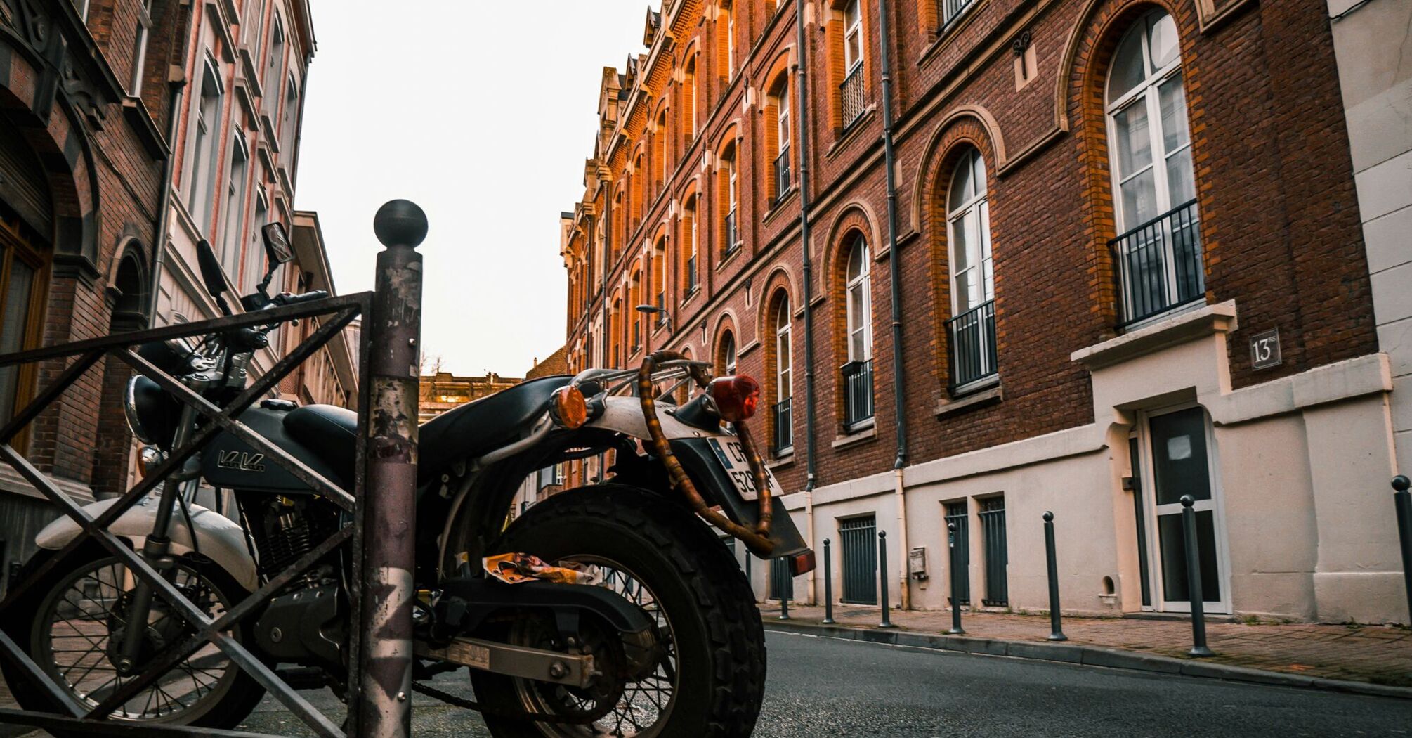 black motorcycle parked beside brown concrete building during daytime