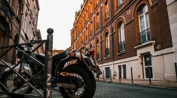 black motorcycle parked beside brown concrete building during daytime