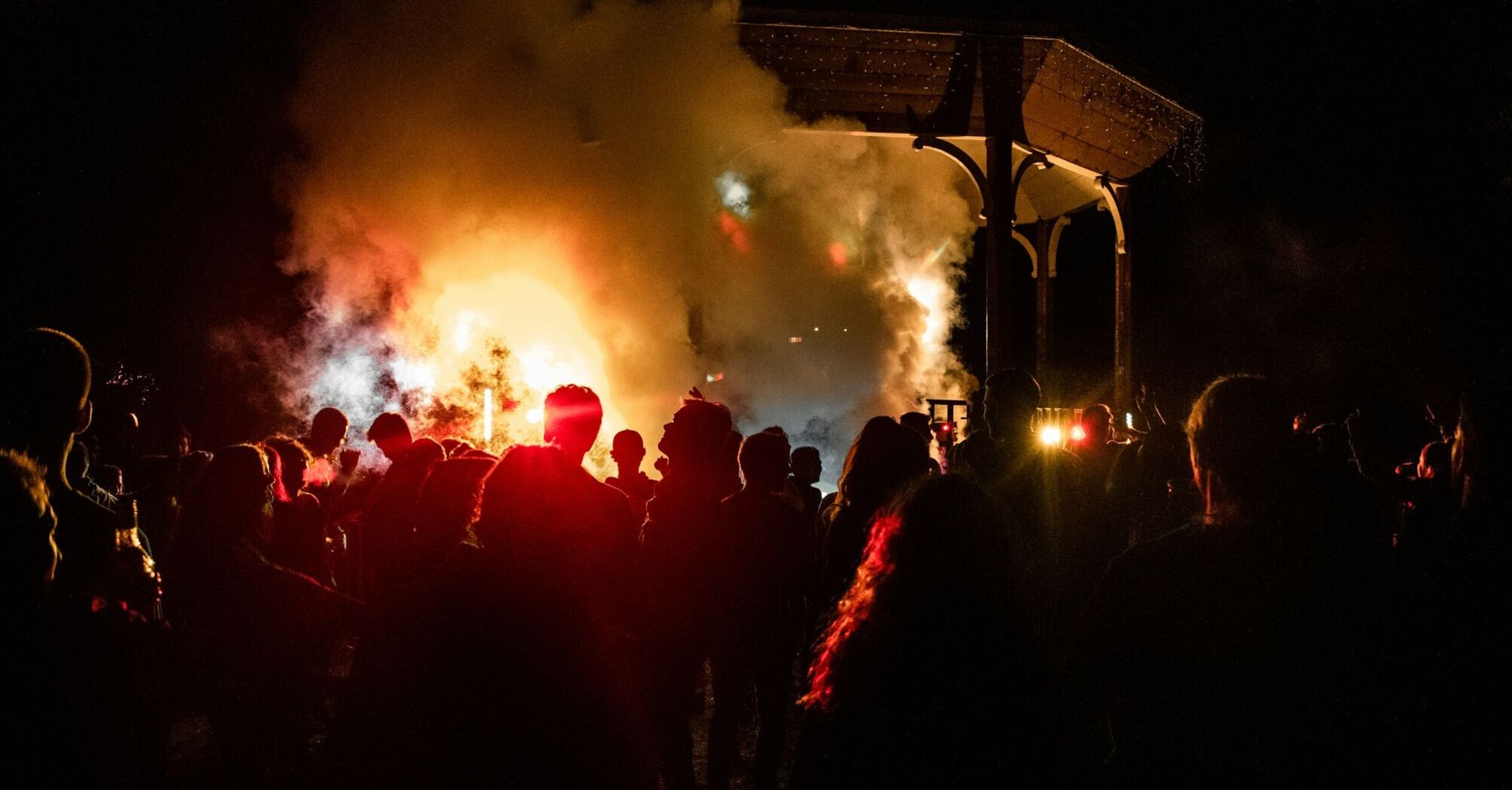 Crowd watching fire and smoke during a festival at night