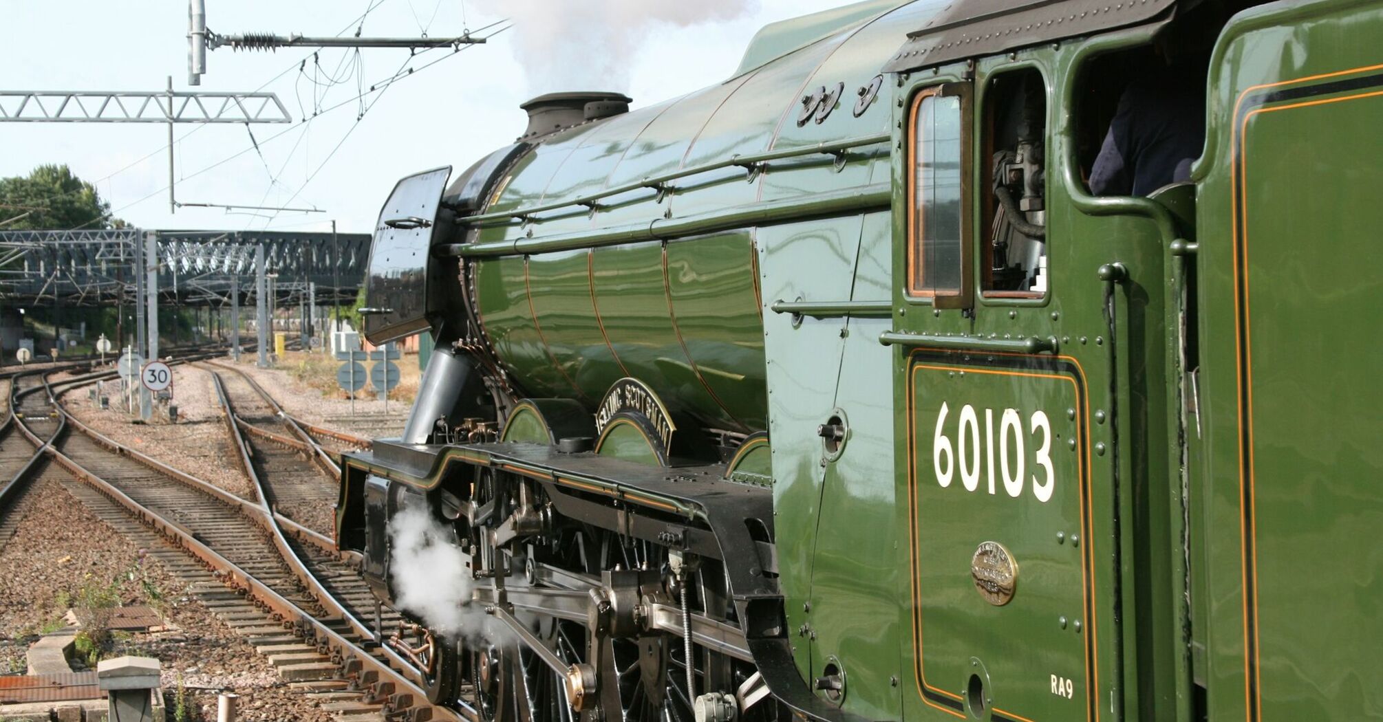 Close-up of a green steam locomotive moving on railway tracks