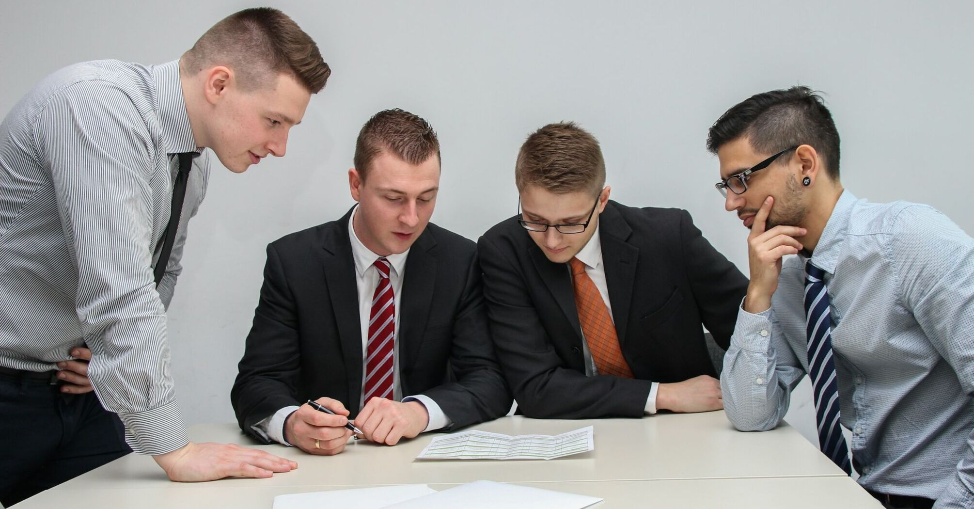 A group of four professionals in business attire discussing documents during a meeting