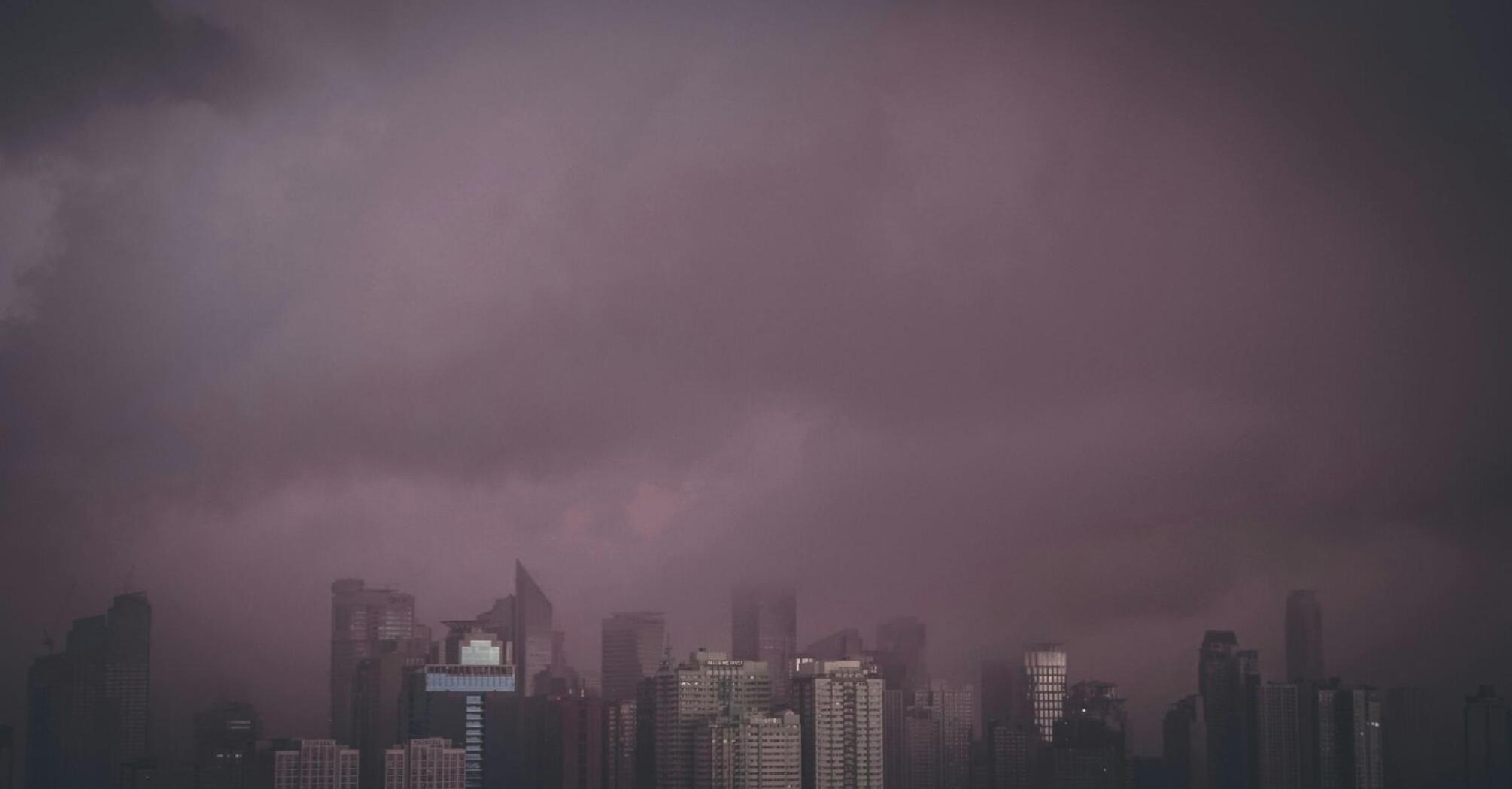 A dark sky looms over a city skyline, suggesting severe weather conditions