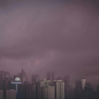 A dark sky looms over a city skyline, suggesting severe weather conditions