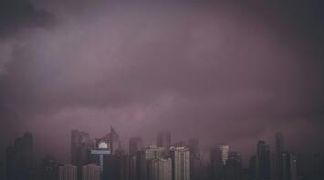 A dark sky looms over a city skyline, suggesting severe weather conditions