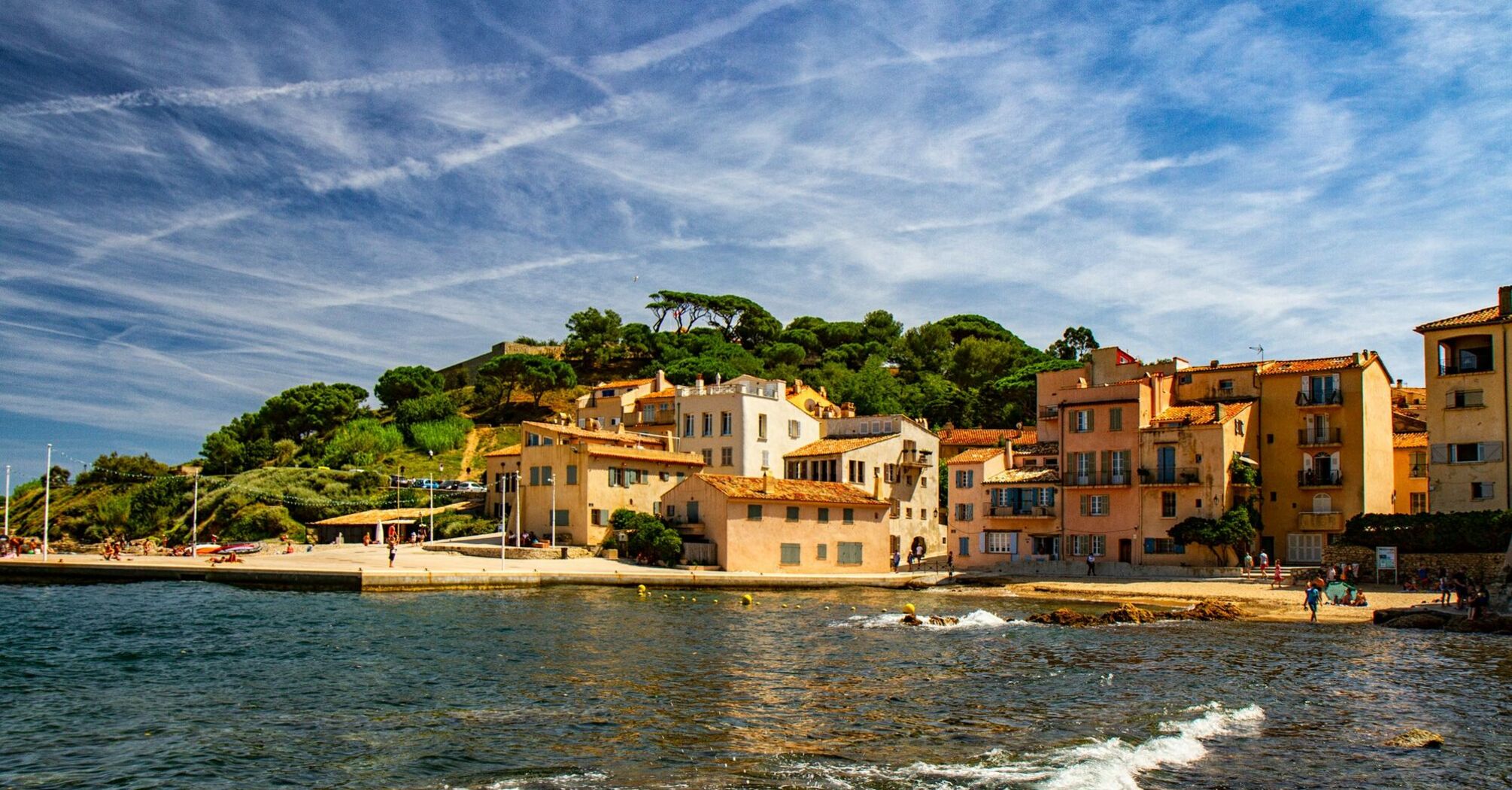 A scenic coastal view of Saint-Tropez, with traditional Mediterranean buildings and a clear blue sky