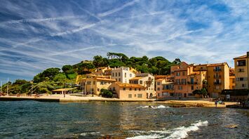 A scenic coastal view of Saint-Tropez, with traditional Mediterranean buildings and a clear blue sky