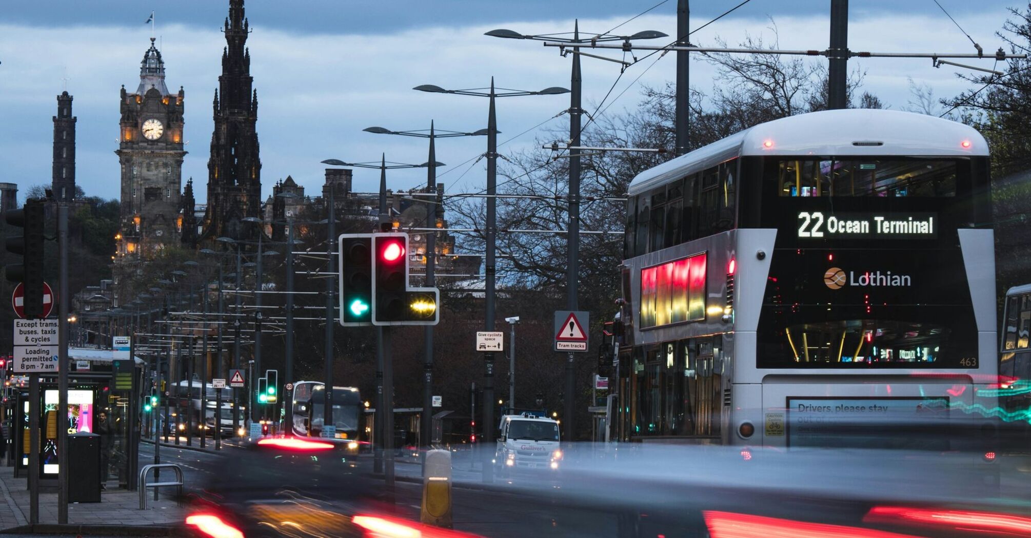 A Lothian bus heading to Ocean Terminal on a busy Edinburgh street at dusk with historical buildings in the background