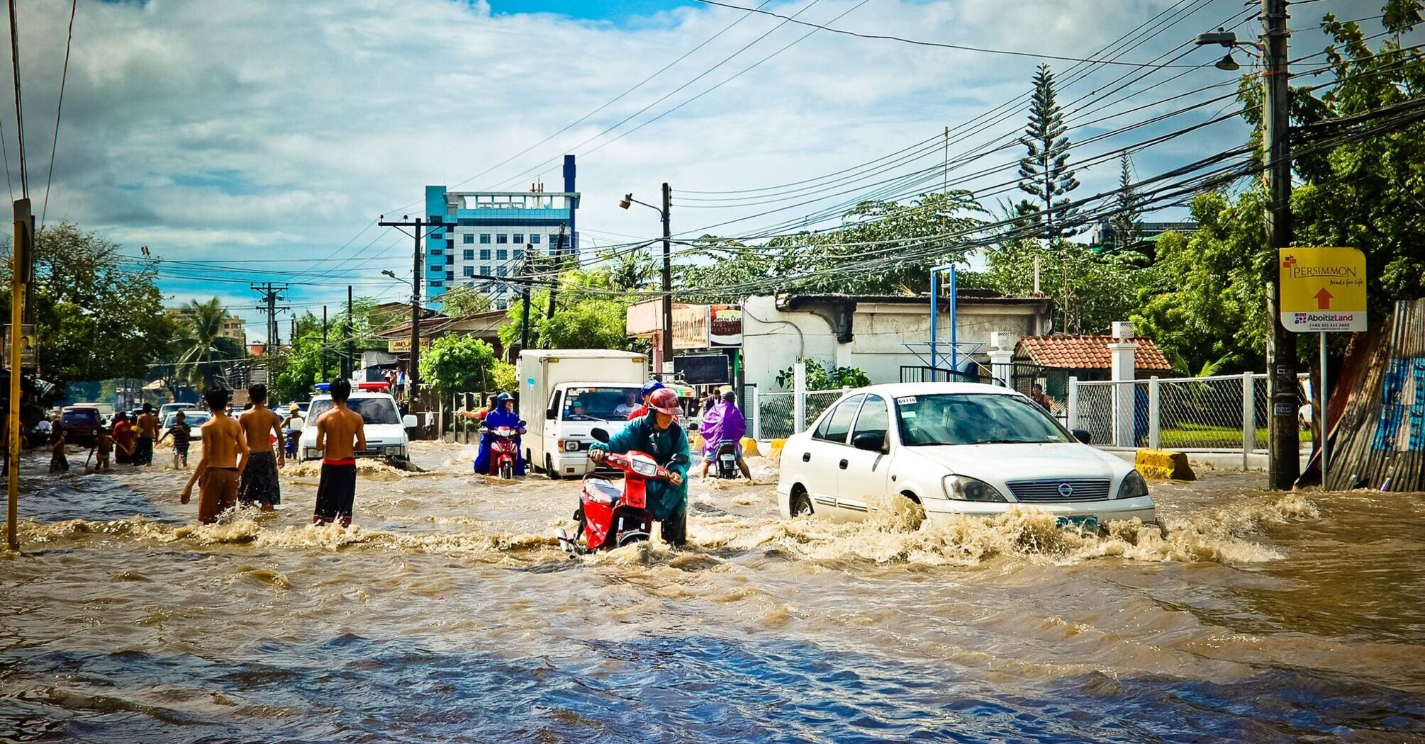 Flooded street with vehicles and people wading through water