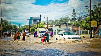 Flooded street with vehicles and people wading through water